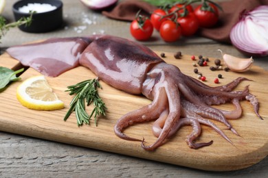 Fresh raw squid with lemon, rosemary and pepper on wooden table, closeup