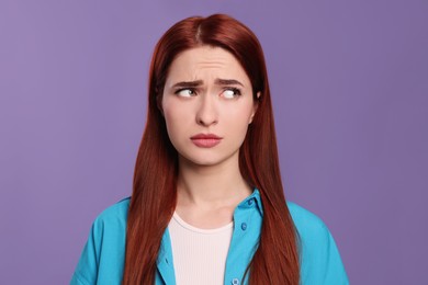 Photo of Confused woman with red dyed hair on purple background
