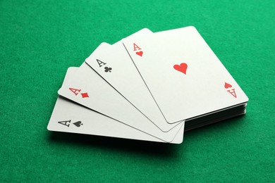 Photo of Four aces playing cards on green table, closeup. Poker game