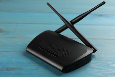Modern Wi-Fi router on light blue wooden background