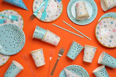 Disposable tableware on orange background, flat lay
