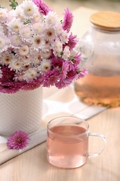 Fresh delicious herbal tea and beautiful bouquet on wooden table