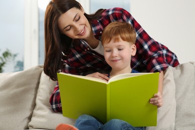 Happy mother reading book with her child at home
