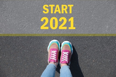 Text Start 2021 on asphalt in front of woman, top view