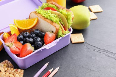 Lunch box with healthy food and pencils on black textured table, space for text