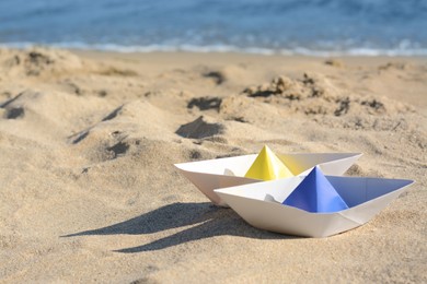 Photo of Two paper boats near sea on sunny day, space for text