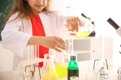 Schoolchild making experiment at table in chemistry class, closeup