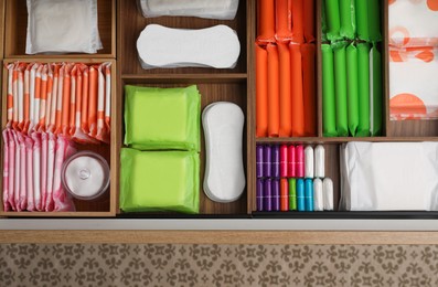 Storage of different feminine hygiene products in wooden drawer, top view