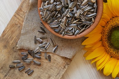Organic sunflower seeds and flower on wooden table, flat lay