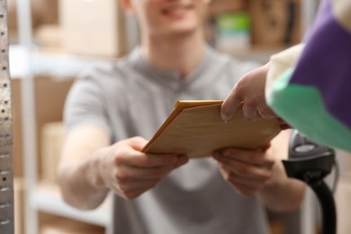 Worker giving parcel to woman at post office, closeup