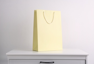 Paper shopping bag on white chest of drawers against light background