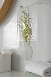 Silicone vase with flowers on white marble wall over countertop in bathroom