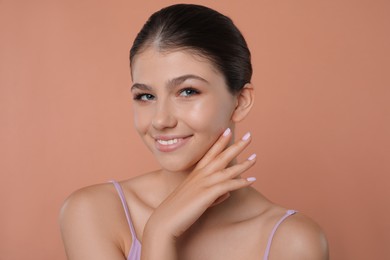 Portrait of pretty girl on pale coral background. Beautiful face with perfect smooth skin