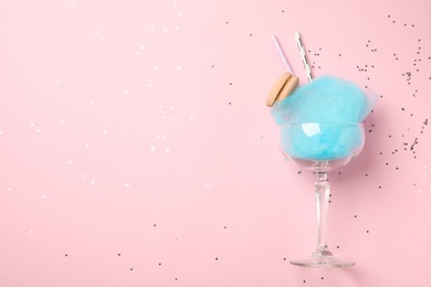 Photo of Glass with cotton candy and macaroon on pink background, top view. Space for text