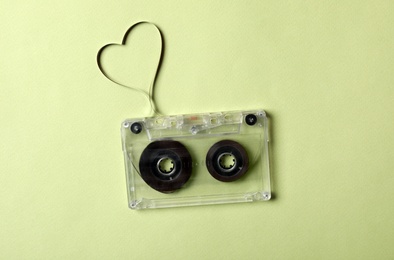 Music cassette and heart made with tape on green background, top view. Listening love song