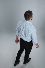Photo of Man in formal clothes on grey background, back view