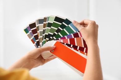 Female interior designer with color palette samples on light background, closeup