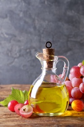 Jug of natural grape seed oil on wooden table. Organic cosmetic