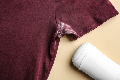 Clothes with stain and deodorant on beige background, closeup