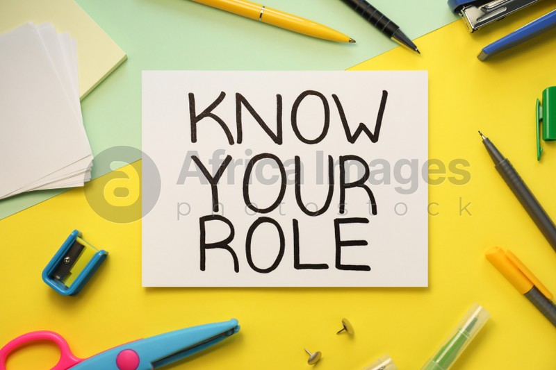 Note with phrase Know Your Role and stationery on color background, flat lay