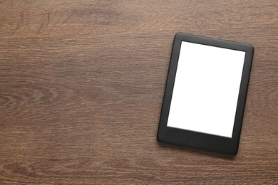 Modern e-book reader with blank screen on wooden table, top view. Space for text