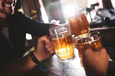 Friends clinking glasses with beer in pub, closeup