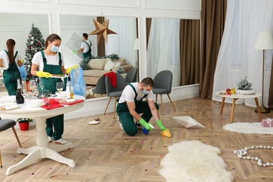 Photo of Cleaning service team working in messy room after New Year party