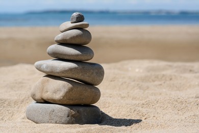 Stack of stones on beautiful sandy beach near sea, space for text