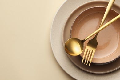 Stylish empty dishware and cutlery on beige background, top view. Space for text