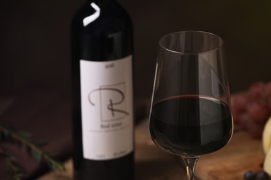 Glass of red wine with bottle on table, closeup