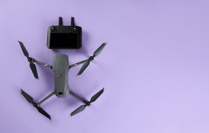 Modern drone with controller on lilac background, flat lay. Space for text