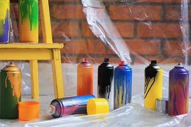 Used cans of spray paints near brick wall indoors. Graffiti supplies