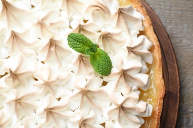 Delicious lemon meringue pie decorated with mint on wooden table, top view