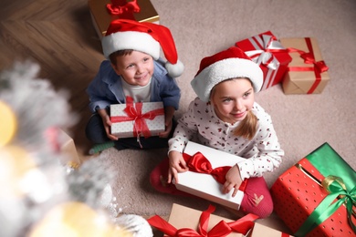 Cute little children with Christmas gifts on floor at home, above view