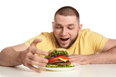Young hungry man and tasty burger on white background