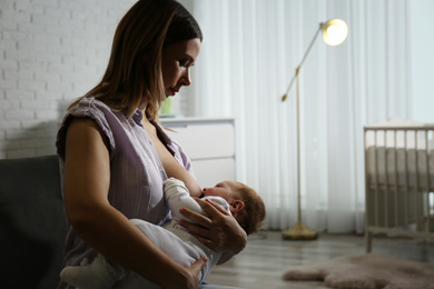 Young woman breast feeding her little baby at home. Space for text