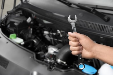 Image of Auto mechanic with wrench near broken down car, closeup