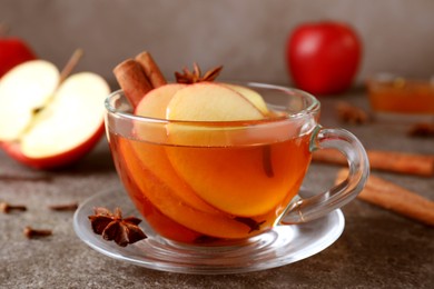Aromatic hot mulled cider on grey table, closeup