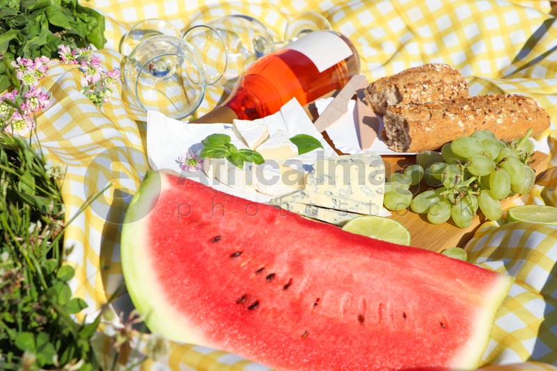 Picnic blanket with delicious food and wine on green grass outdoors, closeup