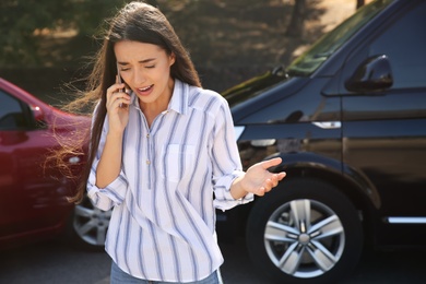 Stressed woman talking on phone after car accident outdoors