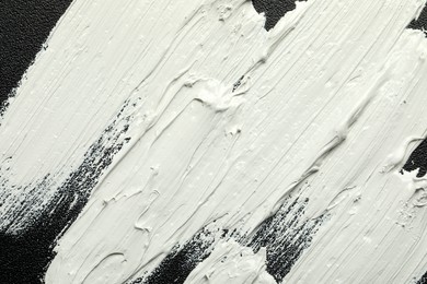 Strokes of white oil paint on black canvas, closeup