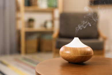Photo of Aroma oil diffuser on wooden table at home, space for text. Air freshener