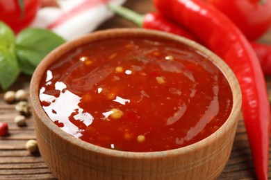 Spicy chili sauce in bowl on wooden table, closeup