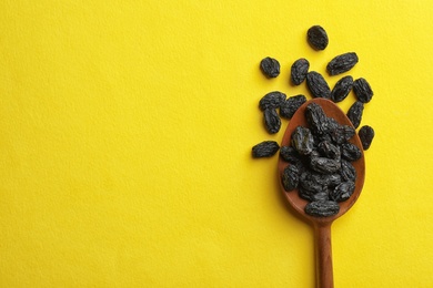 Spoon with raisins and space for text on color background, top view. Dried fruit as healthy snack