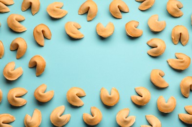 Photo of Frame of tasty fortune cookies with predictions on light blue background, flat lay. Space for text