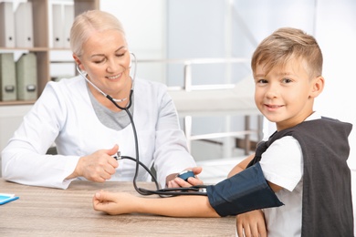 Photo of Little boy visiting doctor in hospital. Measuring blood pressure and checking pulse