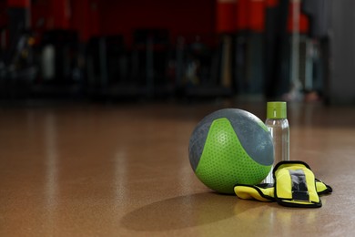 Medicine ball, bottle and weighting agents on floor in gym. Space for text