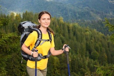 Photo of Woman with backpack and trekking poles hiking in mountains. Space for text