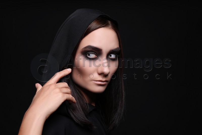 Mysterious witch with spooky eyes on black background
