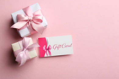 Gift card and presents on pink background, flat lay. Space for text